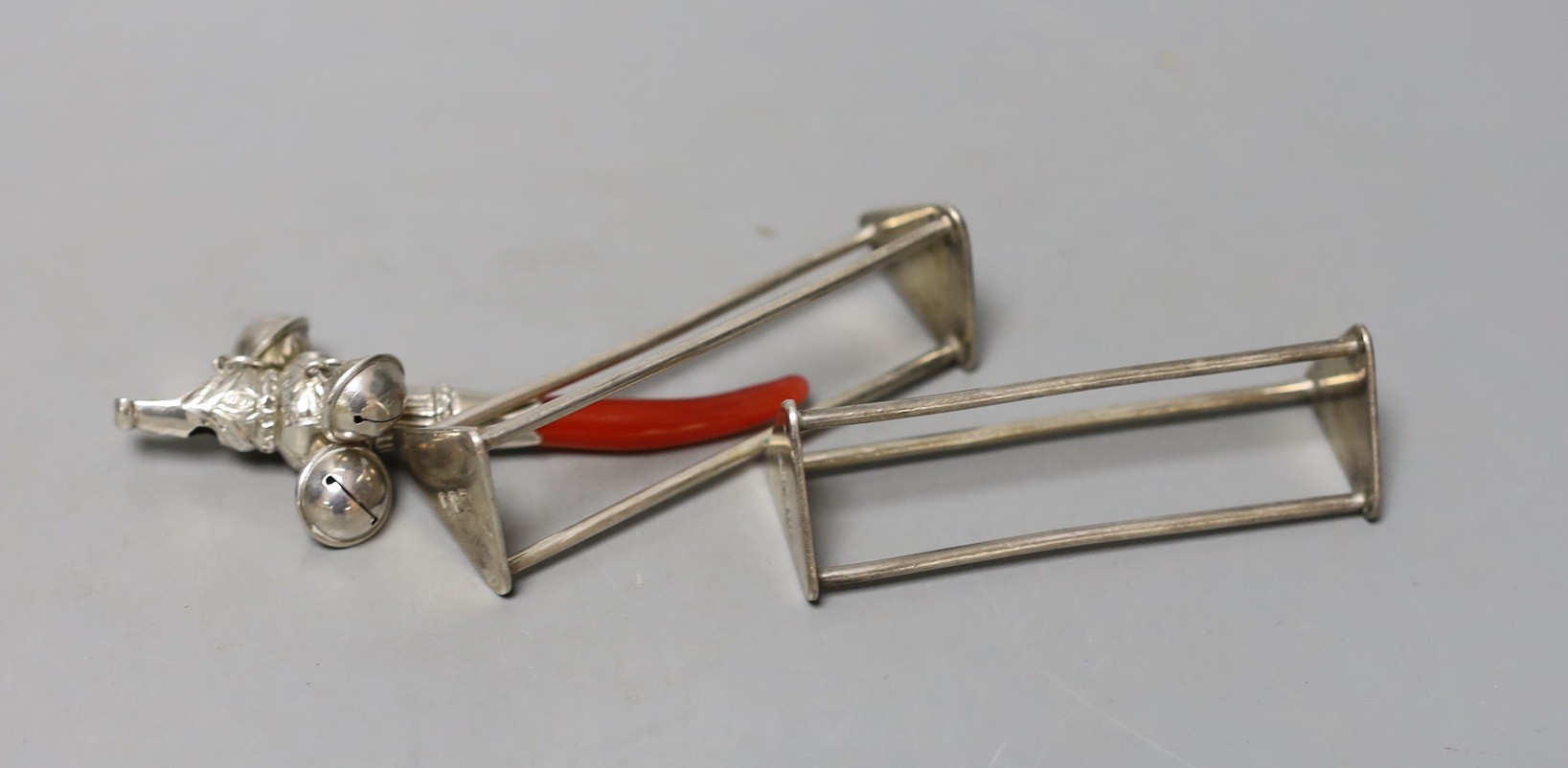 A white metal and coral mounted child's rattle, 81mm together with a pair of George III silver triangular knife rests, John Emes, London, 1799, 69mm.